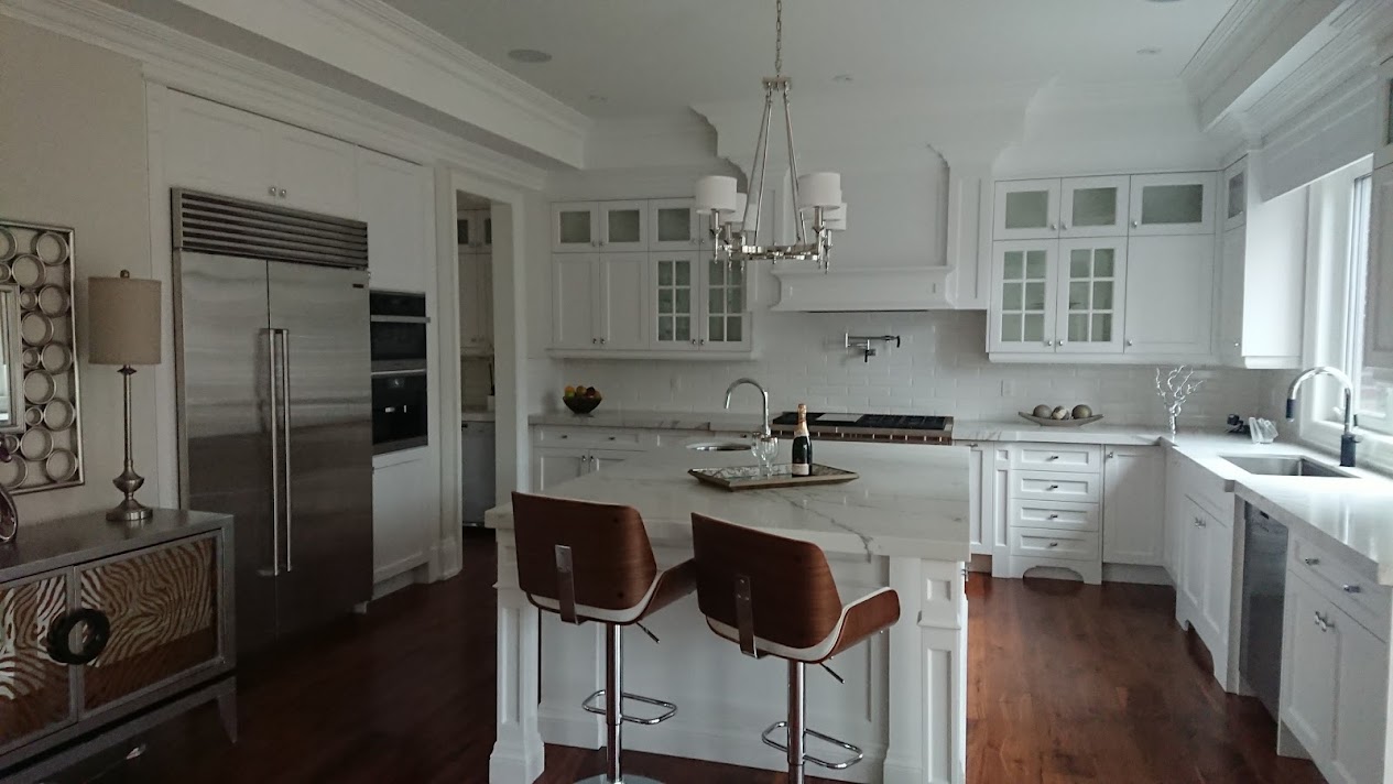 Renovated white kitchen with custom cabinetry, hardwood flooring, and finished trim